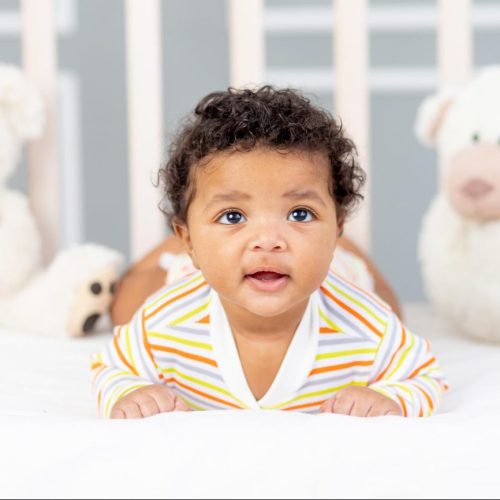 africanamerican-small-child-lying-bed-orange-clothes-with-soft-bears